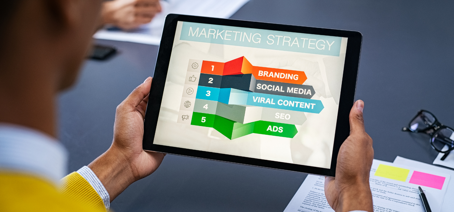 Seorang pria melihat presentasi di tabletnya mengenai strategi pemasaran untuk membuat low season mempengaruhi performance marketing demi keuntungannya
