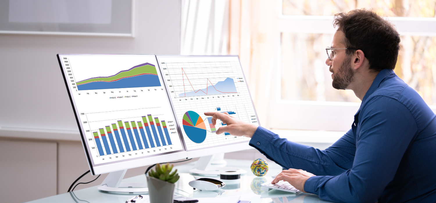 A man wearing a blue formal shirt and glasses analyzes the analytics to understand big data in the hotel industry.