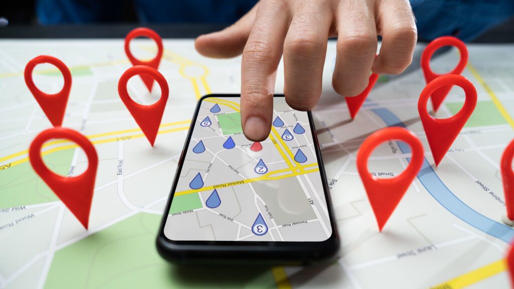 Hand interacting with a smartphone map app with red location pins.